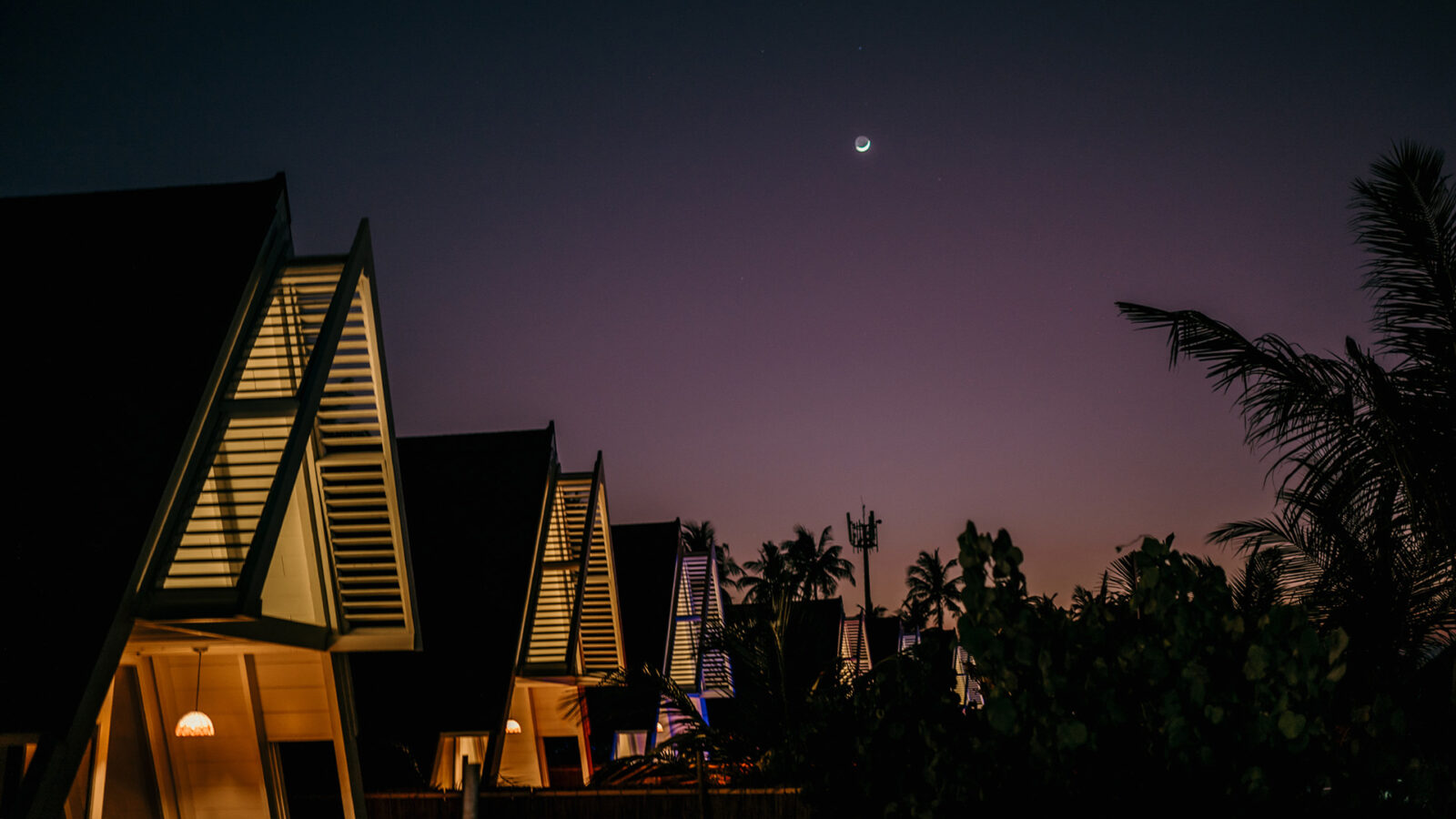 Houses on a Maldives Island at night time, with a view of the moon